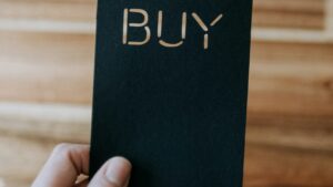 Photo by https://unsplash.com/@kellysikkema on https://unsplash.com/photos/a-person-holding-up-a-black-book-with-the-word-buy-written-on-it-ZbJfBi8H7KM